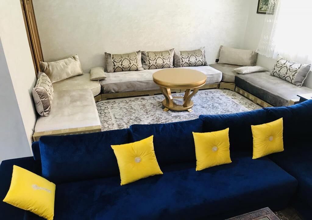 A living room with a blue sofa, a beige sectional sofa, and a round coffee table.