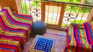 A balcony with striped cushions, a round ottoman, and a tiled table. - Beautiful apartment in Ricoflores Beach 4386 (Mohammedia)