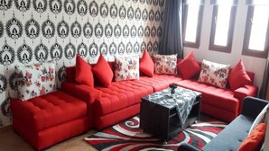 A living room with a red sofa set, a black coffee table, and a patterned rug. - Beautiful apartment in Lilacs Garden 4539 (Cabo Negro)
