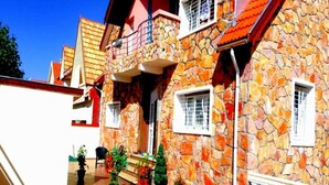 A stone building with a tiled roof, a balcony, and potted plants. - Sublime Floor Villa in Ifrane 4172 (Ifrane)