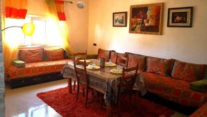 A cozy living room with a sofa set, a dining table with chairs, and a red rug. - Sublime Floor Villa in Ifrane 4172 (Ifrane)