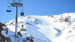 A ski lift chair suspended from a cable on a snowy mountain. - Sublime Floor Villa in Ifrane 4172 (Ifrane)