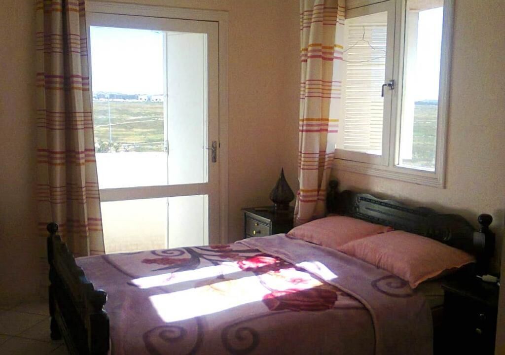 Ein Schlafzimmer mit Bett, Vorhängen, Fenster und Nachttisch.