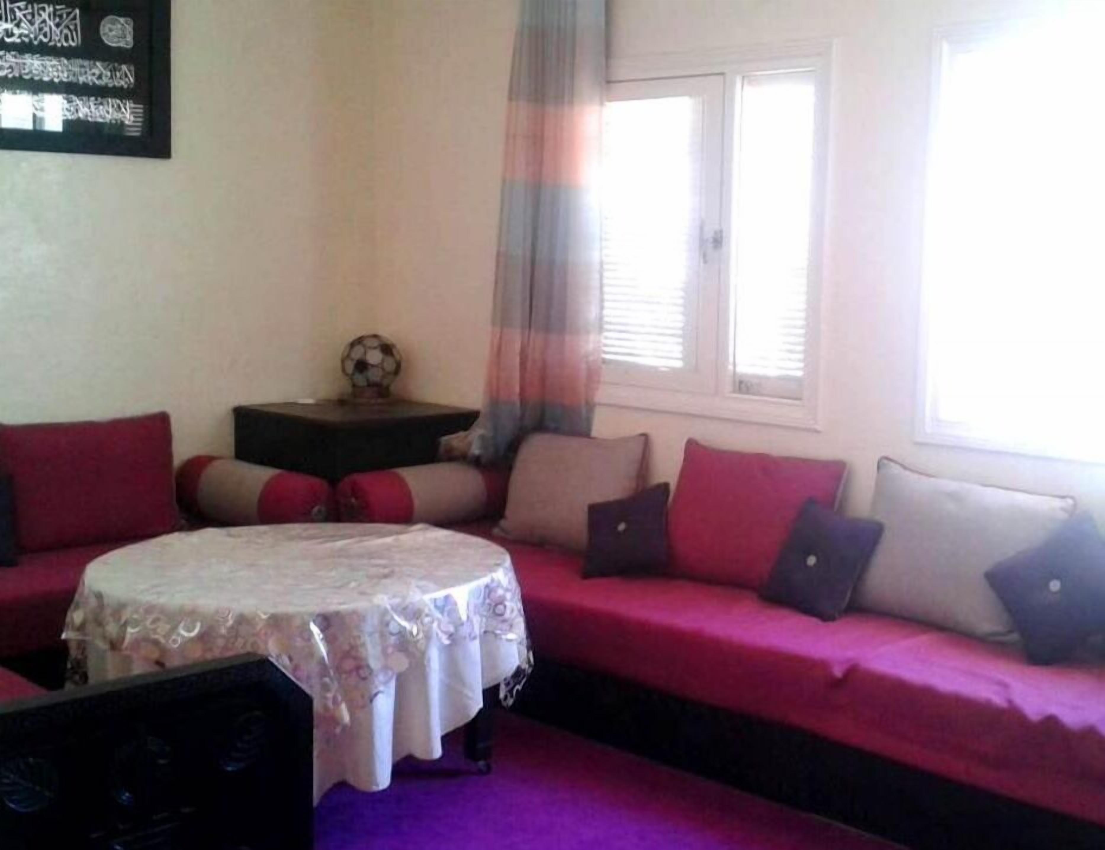 Una habitación acogedora con un conjunto de sofás, una pequeña mesa con un balón de fútbol y una ventana con persianas.
