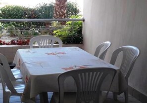 En balkon med bord og stole, omgivet af grønt.