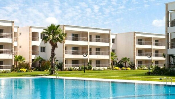 Un hotel con piscina, varios balcones y un césped bien cuidado.