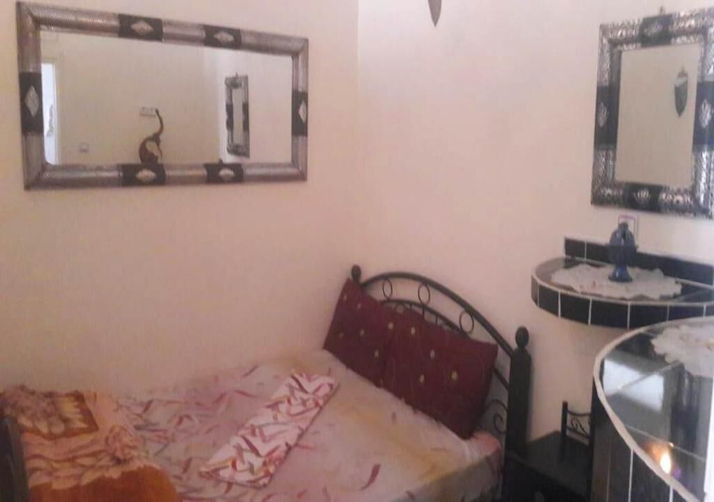 Une chambre à coucher avec un lit, une table de chevet, un miroir et une petite table.