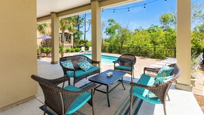 An outdoor patio with wicker furniture and a pool in the background. - Destin Sun | Private Pool | 6-Seater Golf Cart | 4 Mins to Beach (Destin)