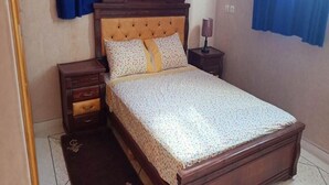 Una camera da letto con un letto in legno, un comodino, un cassetto e una tavola notte con una lampada.