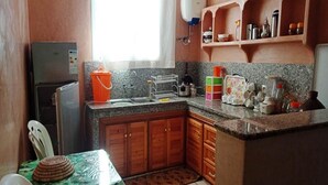 Cucina con mobili in legno, un piano di lavoro in granito, un lavello e un tavolo con tovaglia verde.
