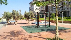 An outdoor area with a playground, benches, and trees.