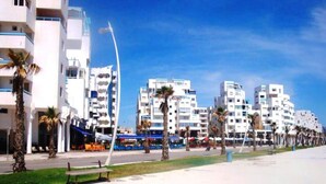 A coastal urban area with modern buildings, palm trees, and a clear sky. - Nice Studio of seaside 4376 (Martil)
