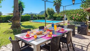 An outdoor dining area with a table set for breakfast, overlooking a swimming pool and lush greenery. - LES MURTERETES   ref. VP79 (Pollensa / Pollença)