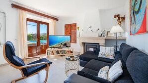 A living room with a sofa, armchair, TV, bookshelf, and a fireplace. - LES MURTERETES   ref. VP79 (Pollensa / Pollença)