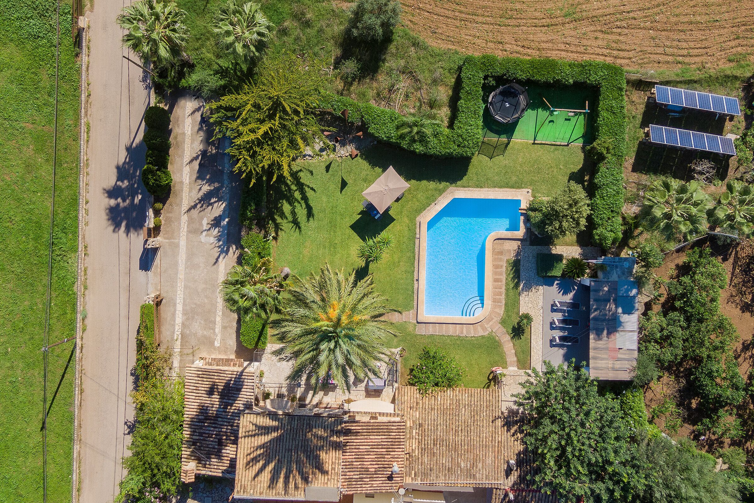 Vue aérienne d’une propriété dotée d’une piscine, de panneaux solaires et d’un court de tennis.