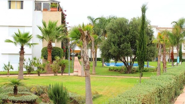 Un jardin aménagé avec des palmiers, une piscine et un bâtiment doté de balcons.