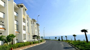 A coastal road lined with white buildings, palm trees, and a clear view of the sea. - Sublime apartment with sea and golf views 4301 (Asilah)