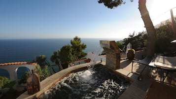 Relax by the serene water feature, surrounded by a wooden deck and scenic sea views.