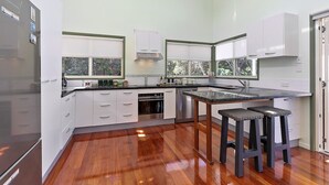 Una cocina moderna con armarios blancos, un refrigerador de acero inoxidable y piso de madera.