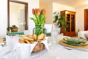 Ein Esstisch mit einem Brotkorb, einem Tulpenstrauß und klarem Glasgeschirr.