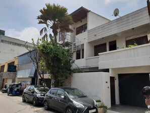 A street view with parked cars, a building with a satellite dish, and a sign for 'TURNKEY'. - Trellis Apartment (Colombo)