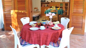 Un coin repas avec une table dressée pour quatre personnes, entourée de chaises blanches.
