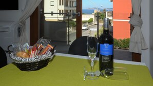 A table with a bottle of wine, a glass, and a basket of bread and snacks. - ALKIRA LODGE - ILUKA Two-bedroom apartment with sea view (Alghero)
