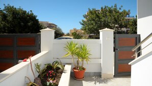 A gated residential area with a potted plant, a small garden, and a staircase leading to a building. - ALKIRA LODGE - ILUKA Two-bedroom apartment with sea view (Alghero)