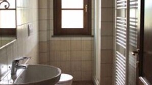 A bathroom with a sink, two toilets, a window, and a radiator. - Apartment Rosa 4 + 1 (Lajatico)