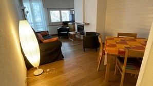 Un espace de vie compact comprenant un coin repas, un canapé, une table et une cheminée.
