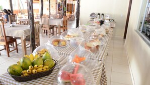 A buffet table with covered food items and a fruit basket. - Requinte Hotel (Altamira)