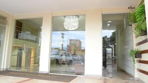 A hotel entrance with a glass door, a chandelier, and a staircase leading to an upper level. - Requinte Hotel (Altamira)