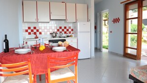 Eine moderne Küche mit weißen Schränken, einer roten Küchentuch-Rückwand und einem Essbereich mit rotem Tischläufer und orangefarbenen Stühlen.