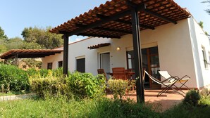 Ein Haus mit einer Terrasse, Sitzgelegenheiten im Freien und einer Pergola.