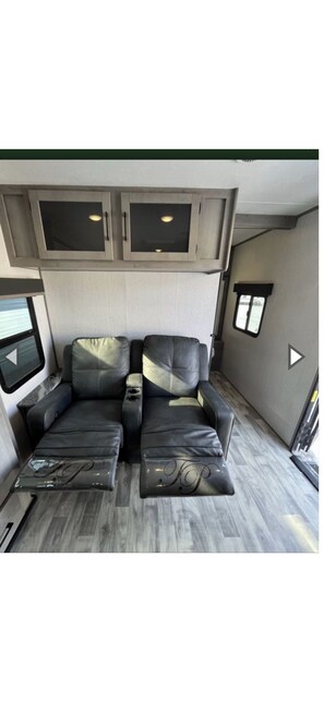 A compact living space with two leather sofas, a small table, and built-in cabinets.