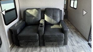 Interno di un camper compatto con divano, mobili contenitori e una finestra.