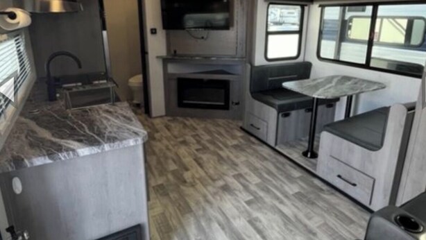 Cucina compatta per camper con fornello integrato, lavello e una piccola zona pranzo.