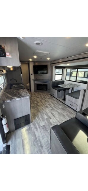 A compact RV kitchen with a built-in stove, a sink, and a small dining area.