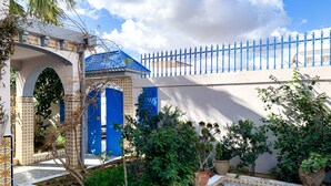 A courtyard with a blue gate, tiled pathway, and potted plants. - House with garden in a residential area 100 m from a magnificent beach (Unknown)