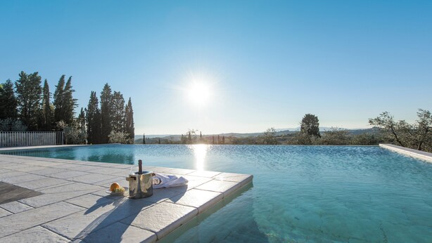 A clear swimming pool with a sun reflecting off the water, surrounded by trees and a distant view of hills. - FARM THE PRINCIPIN Apartment 5  (Vinci FI)