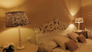 A bedroom with a bed, pillows, a bedside table with a lamp, and a decorative headboard. - FARM THE PRINCIPIN Apartment 5  (Vinci FI)