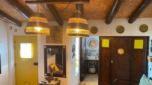 A room with exposed wooden beams, a yellow door, a bed with a striped pillow, and a wooden cabinet. - MILL HOUSE 1 - HOLIDAY HOUSE (Santa Cruz - Torres Vedras)