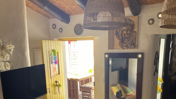 A room with a wooden ceiling, a wicker chair with a yellow cushion, a wooden dresser, and a mirror. - MILL HOUSE 1 - HOLIDAY HOUSE (Santa Cruz - Torres Vedras)