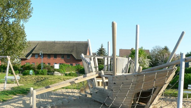 A playground with a ship-shaped climbing structure, swings, and a sandbox. - Apartment 16 - apartment / apartment in Binz (Binz)
