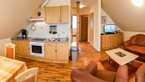 A compact living space with a kitchenette, a dining area, and a seating area with a sofa and chairs. - Apartment 16 - apartment / apartment in Binz (Binz)