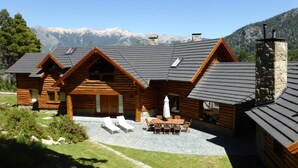 A log cabin with a patio, outdoor seating, and a mountain backdrop.