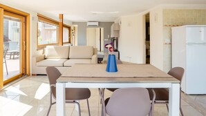 A modern kitchen with a dining area, a sofa, and a table with chairs.