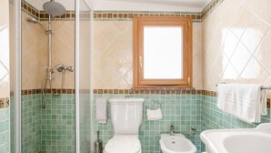 A bathroom with a shower, toilet, bidet, and bathtub.