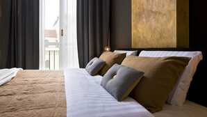 Une chambre d’hôtel avec un grand lit, des rideaux épais, une vue sur les bâtiments environnants et un mur à texture.