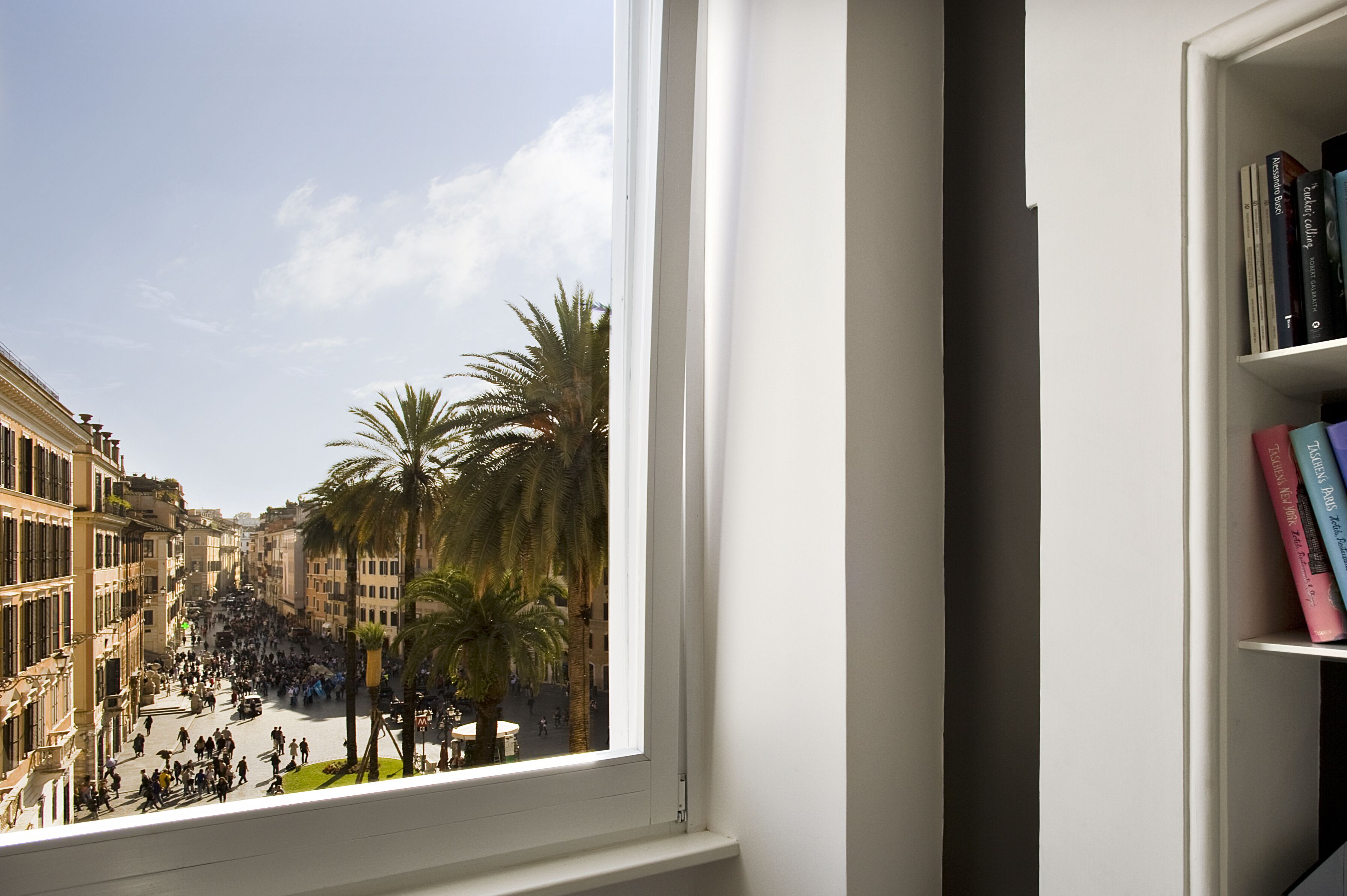 A view from a window overlooking a busy street with palm trees and historic buildings.